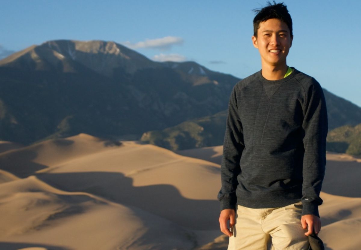 Alex Lee outside with mountains and sand dunes in the background